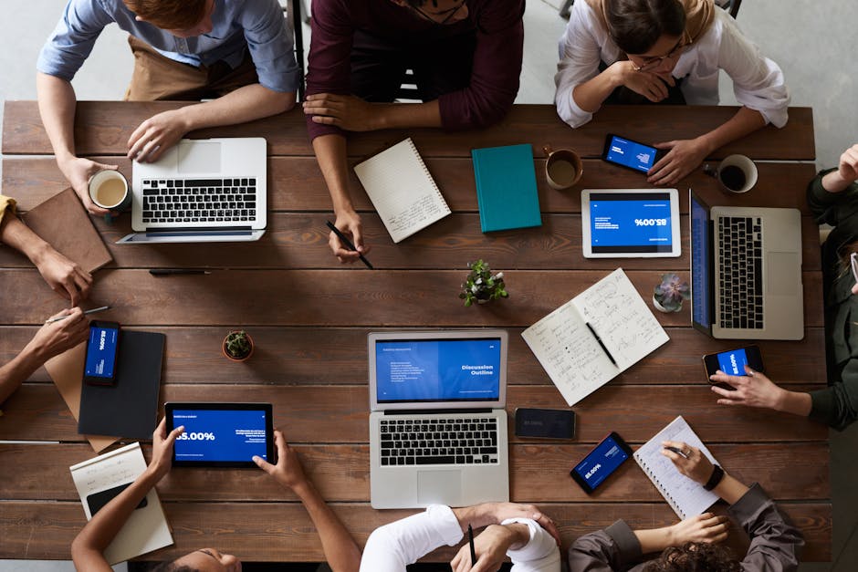 Overhead view of a diverse team in a business meeting using laptops and tablets.